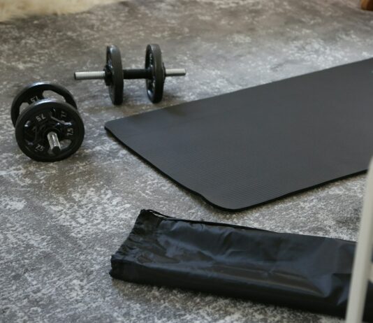 하루 20분 운동의 기적: 건강의 비결 a pair of dumbbells and a black mat on the floor
