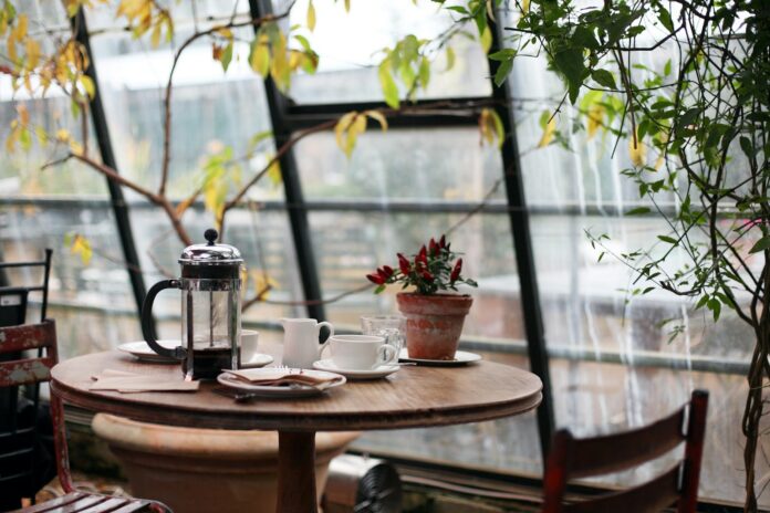 Photo by Kris Atomic round brown wooden table with french press on top with white ceramic teacup beside