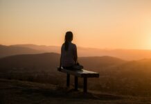 스트레스를 마주하는 방식이 신경계와 면역에 스며드는 보이지 않는 영향 woman sitting on bench over viewing mountain
