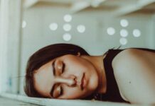 “끊이지 않는 피곤함, 만성피로 극복을 위한 생활 속 신선한 변화” woman resting her head on brown wooden panel bed while closing her eyes