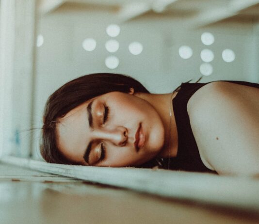 “끊이지 않는 피곤함, 만성피로 극복을 위한 생활 속 신선한 변화” woman resting her head on brown wooden panel bed while closing her eyes