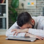 만성피로, 일상에서 벗어나기…작은 변화가 만드는 큰 힘 a man sitting at a desk with his head in his hands