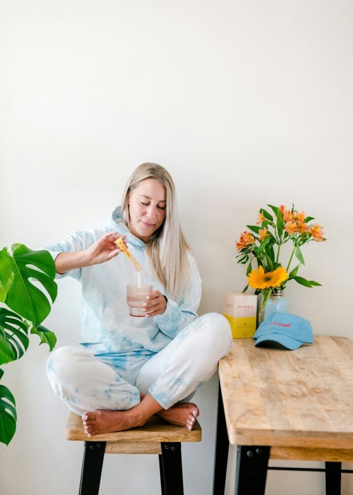 Photo by Marea Wellness a woman sitting on a stool holding a drink
