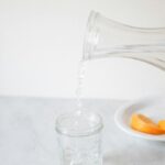 똑똑한 수분 섭취, 건강 지키는 작은 습관의 힘 A person pouring water into a glass on a table